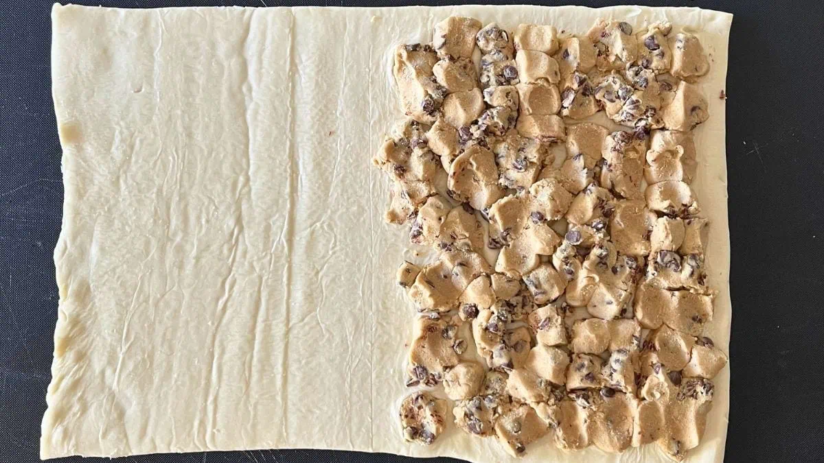 pastry pinwheels on a flat piece of dough with cookie dough smashed down