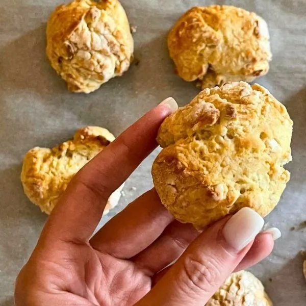 yeast biscuits on a baking sheet with a hand holding one